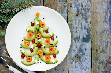 Delicious edible Christmas tree from avocado slices, salty salmon, cranberry and boiled egg stars...