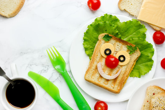 Funny clown face grilled sandwich with cheese and vegetables for kids lunch top view