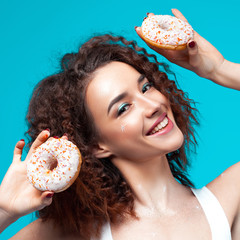 Beautiful young cheerful girl with donuts in hand