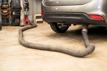 Car undergoing repair or a service in a workshop with focus to the exhaust pipe