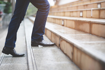 modern businessman working close-up legs walking up the stairs in modern city. in rush hour to work...