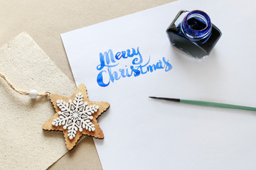 Merry Christmas - calligraphy, handwritten letters on white paper.