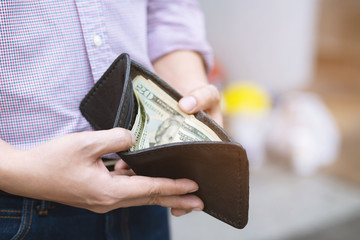 close up Businessman plaid shirt holding an wallet in the hands of an man take money out of pocket. expenses finance concept	