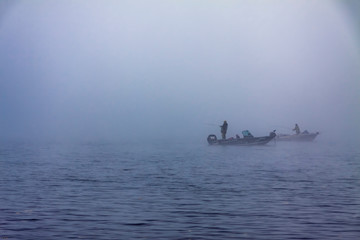 Fishermen catch fish on a boat in the fog in the autumn.