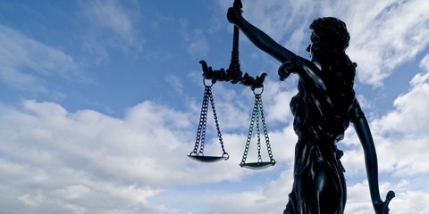 Silhouette of lady justice against a dramatic sky. 