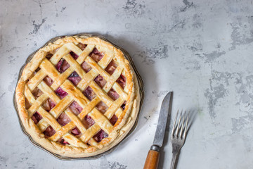 Homemade fruit pie on white stone background.