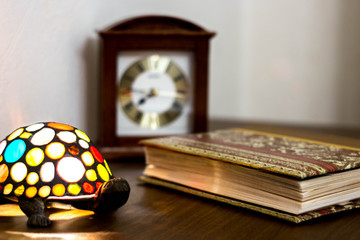 elements of vintage interior: desk clock, book, metal lamp in the shape of a turtle