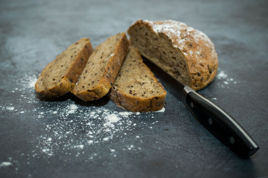 Rustic bread and slices on dark wood fading to black
