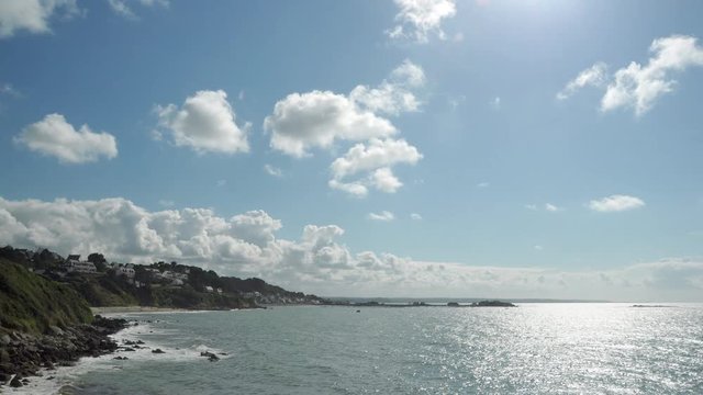 Cinemagraph of a seascape of a bay and a shore in a summer sunny day with white clouds in time-lapse running fast - 4k motion photo.