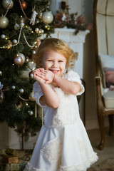 little happy girl sits in an armchair and waits for gifts for the holiday of Christmas and New Year