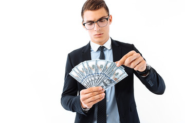 A successful businessman in glasses and a suit, holding dollar bills, carefully recalculates them...