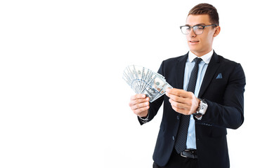 A successful businessman in glasses and a suit, holding dollar bills, carefully recalculates them...