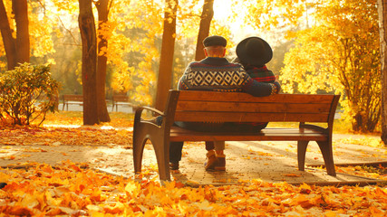 Senior couple enjoying sunset on the bench in the autumn park