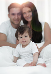 Fototapeta premium Happy couple and son sitting in bed