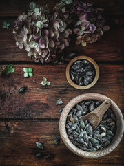 Dry hydrangea, pumpkins, pumpkin oil and seeds in wooden bowls on vintage wood table. Autumn concept. Overhead shot with copy space.