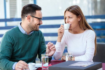 Young couple drinking coffee and talking in an outdoor cafe
