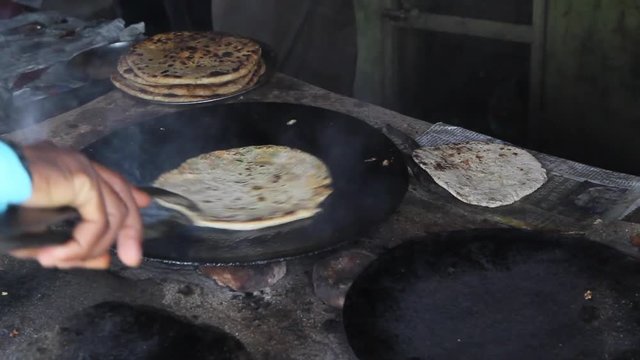 Medium shot of man frying paratha on frying pan