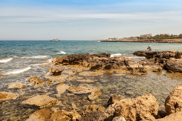 Fototapeta na wymiar Cyprus is a fisherman on the coast of the Mediterranean sea, on the horizon a yacht