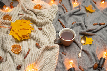 plaid with hot tea and a woolen blanket, autumn yellow leaves and white bulbs. Conception of warmth, comfort, comfort. View from above with empty space for an inscription