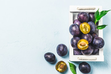 Ripe plums in a box. Top view, space for text.