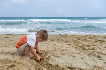 little boy on the beach playing with sand