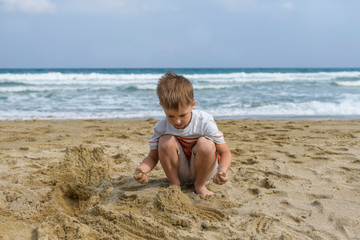 Fototapeta na wymiar little boy on the beach playing with sand