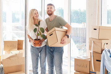 Smiling couple hold boxes in new home. Dreaming new home