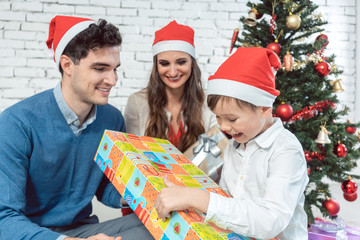 Kind packt Weihnachtsgeschenk zusammen mit Familie aus