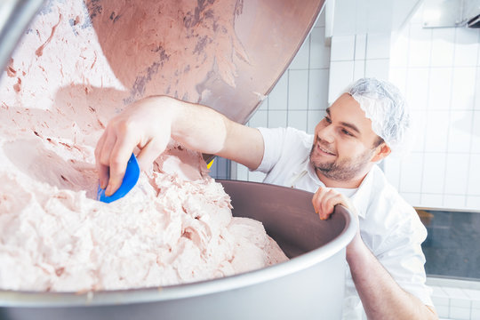 Fleischer zerkleinert Fleisch im Kutter um Wurst daraus zu machen