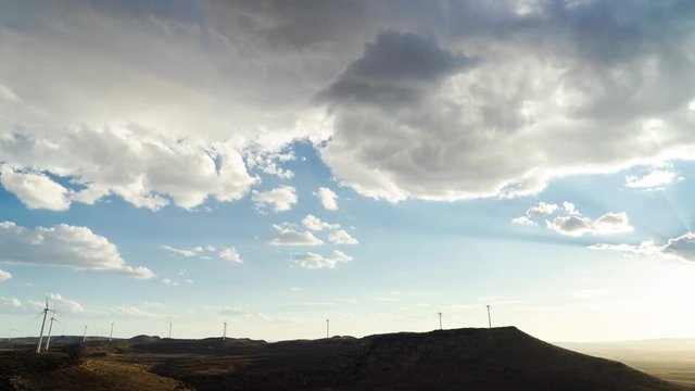4K timelapse wide arid, rocky landscape as clouds clear up, sun breaks through, dramatic golden sunset, streeks of light, Longyuan SA wind turbines (Mulilo) De Aar, Karoo, Northern Cape, wind projects, 25p.