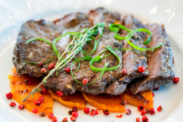 Sliced beef with pumpkin served on white plate
