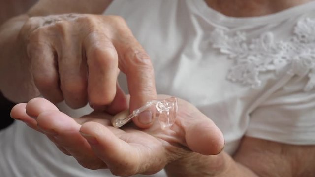 Old Woman Hand Holding Hearing Aid Device