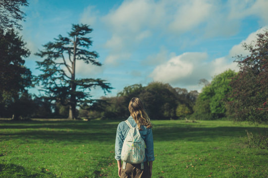 Young woman standing in meadow looking at tree