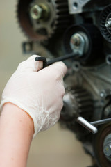 Essex, UK. A gloved hand repairs a car engine.