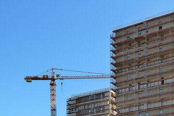 Construction of a high multi-storey building. Skyscraper furnished with metal scaffolding. Dangerous work at height. Modern architecture in the arrangement of the city. Urbanization of the environment