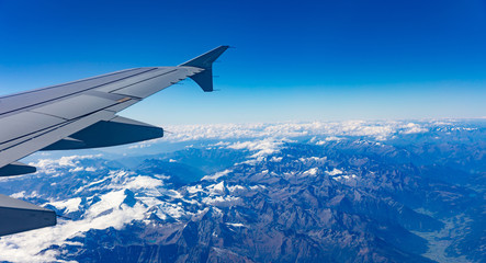 Obraz na płótnie Canvas Mountains and blue sky. View out of an airplane window.
