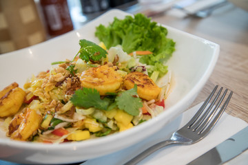 Scharfer Thai Mango Salat mit gebratenen Curry Garnelen, Paprika, Zwiebeln und Koriander im Restaurant