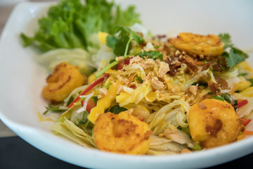 Scharfer Thai Mango Salat mit gebratenen Curry Garnelen, Paprika, Zwiebeln und Koriander im Restaurant