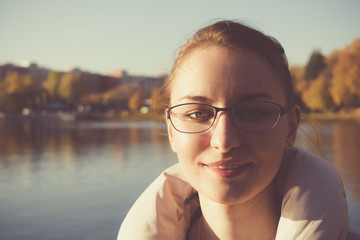 Осенний портрет девушки в очках на фоне водоема. 1