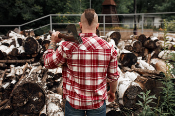 rear view Caucasian bearded mohawk man standing near firewood woodshed