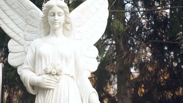 White statue of an angel on the background of the forest