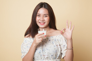 Healthy Asian woman drinking a glass of milk show OK sign.