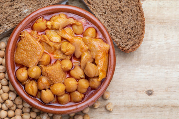 Chickpeas with tripe in clay pot. Aerial (top) view. On wooden background.