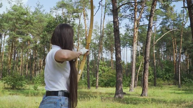 Female archer draving arrow and shooting target