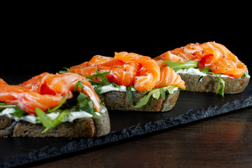 Sandwich with trout and herbs on black slate.