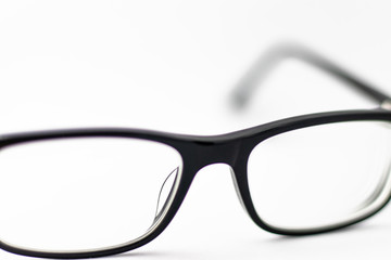 Pair of black glasses lying around on white background
