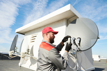 Service worker installing and fitting satellite antenna dish for cable TV