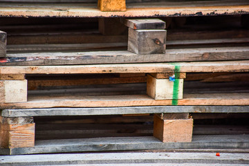 A pile of used wooden pallets is close