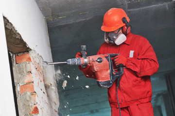 worker with demolition hammer breaking interior wall