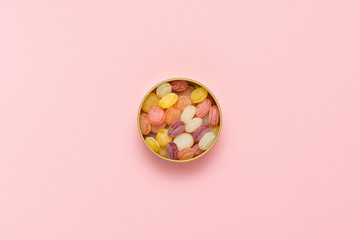 Multicolored lollipops in a round can on a gently pink backgroun